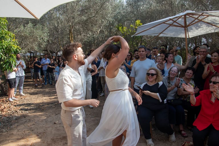 החתן מסובב את הכלה בריקוד, אורחים צופים