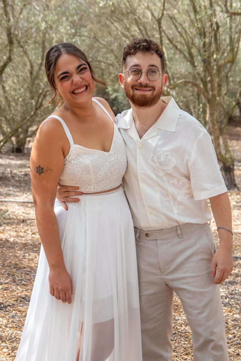הכלה והחתן מחובקים ומחייכים למצלמה