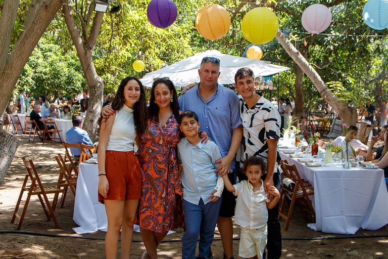 משפחה מצטלמת יחד מתחת לפנסי נייר צבעוניים, מבוגרים וילדים