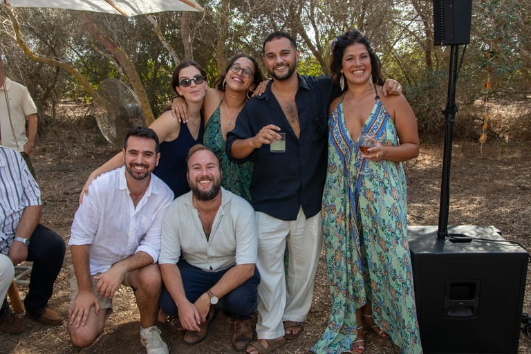 קבוצת חברים מחייכים, חלקם כורעים על הקרקע