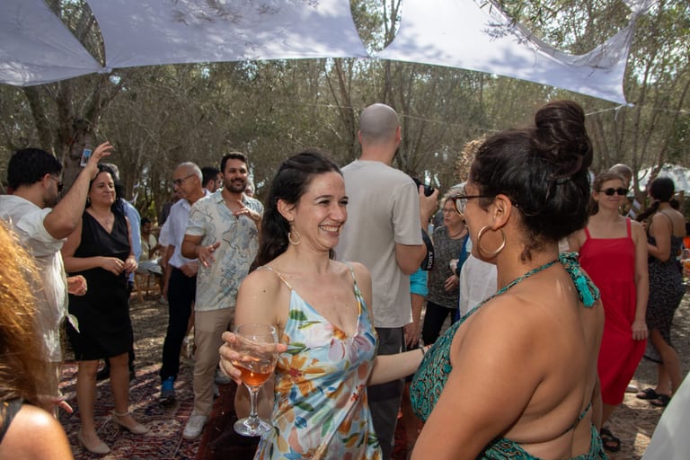 אורחות בשמלות קיץ רוקדות ומשוחחות בין אורחים